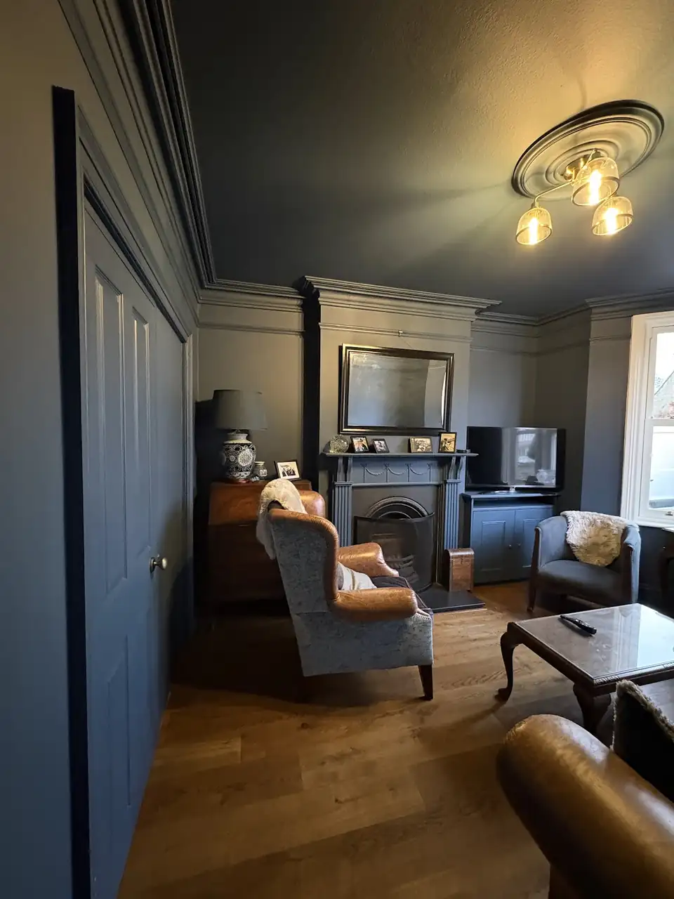 Living room in Cheltenham with deep blue walls, panelled doors and a ceiling rose, decorated by LCL Decorating