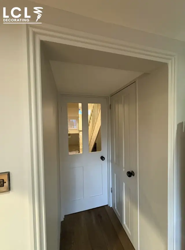 Crisp white hallway walls, door frame and panelled doors after preparation and painting